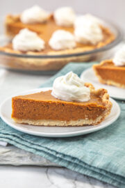 A slice of pumpkin pie without eggs served with a dollop if whipped cream.