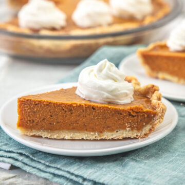 A slice of pumpkin pie without eggs served with a dollop if whipped cream.