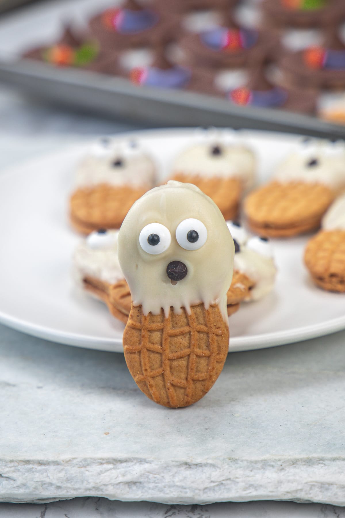 Nutter butter ghost cookies making it stand with the support of a plate.
