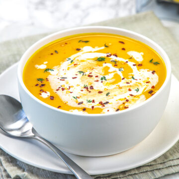 A bow of roasted butternut squash soup with a spoon on the side.