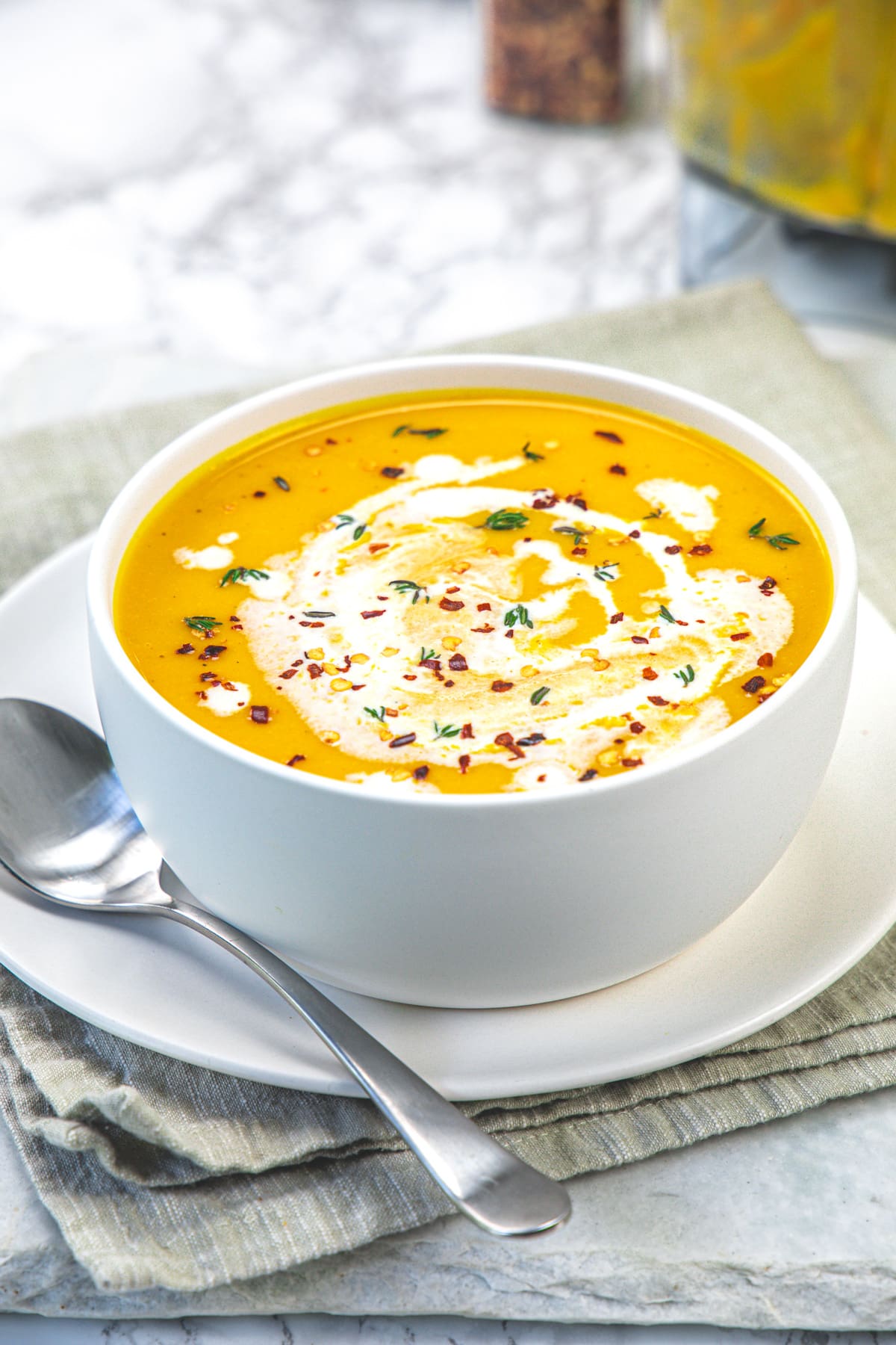 A bow of roasted butternut squash soup with a spoon on the side.