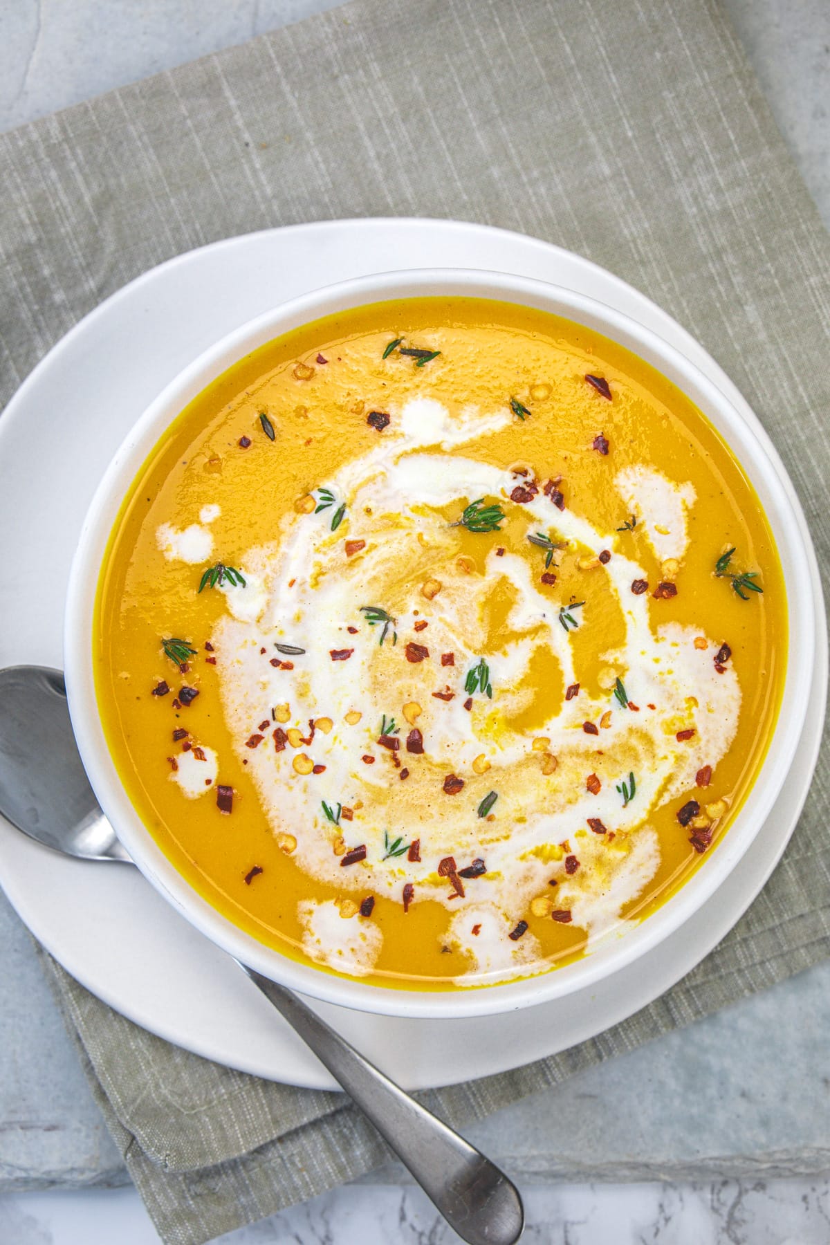 Roasted butternut squash soup served in a bowl with a spoon on the side.