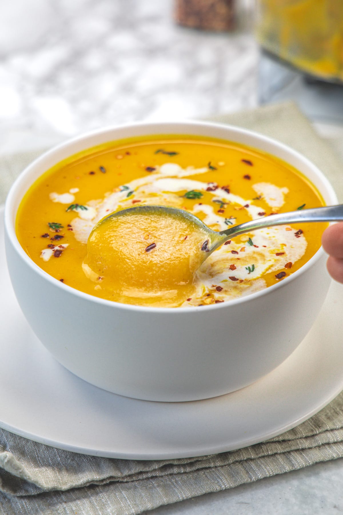 Taking a spoonful of roasted butternut squash soup from the bowl.