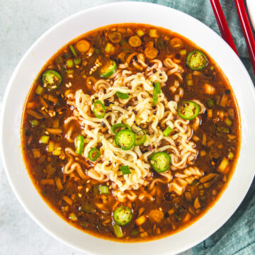 Spicy ramen noodles bowl topped with chili oil, spring onions and green chilies.