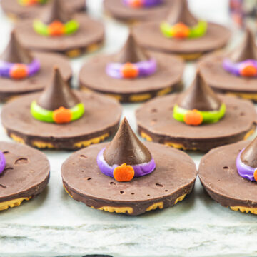 Witch hat cookies arranged on a marble surface.