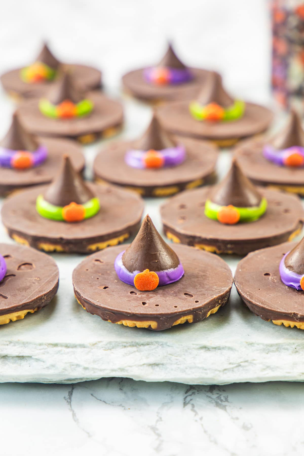 Witch hat cookies arranged on a marble surface.