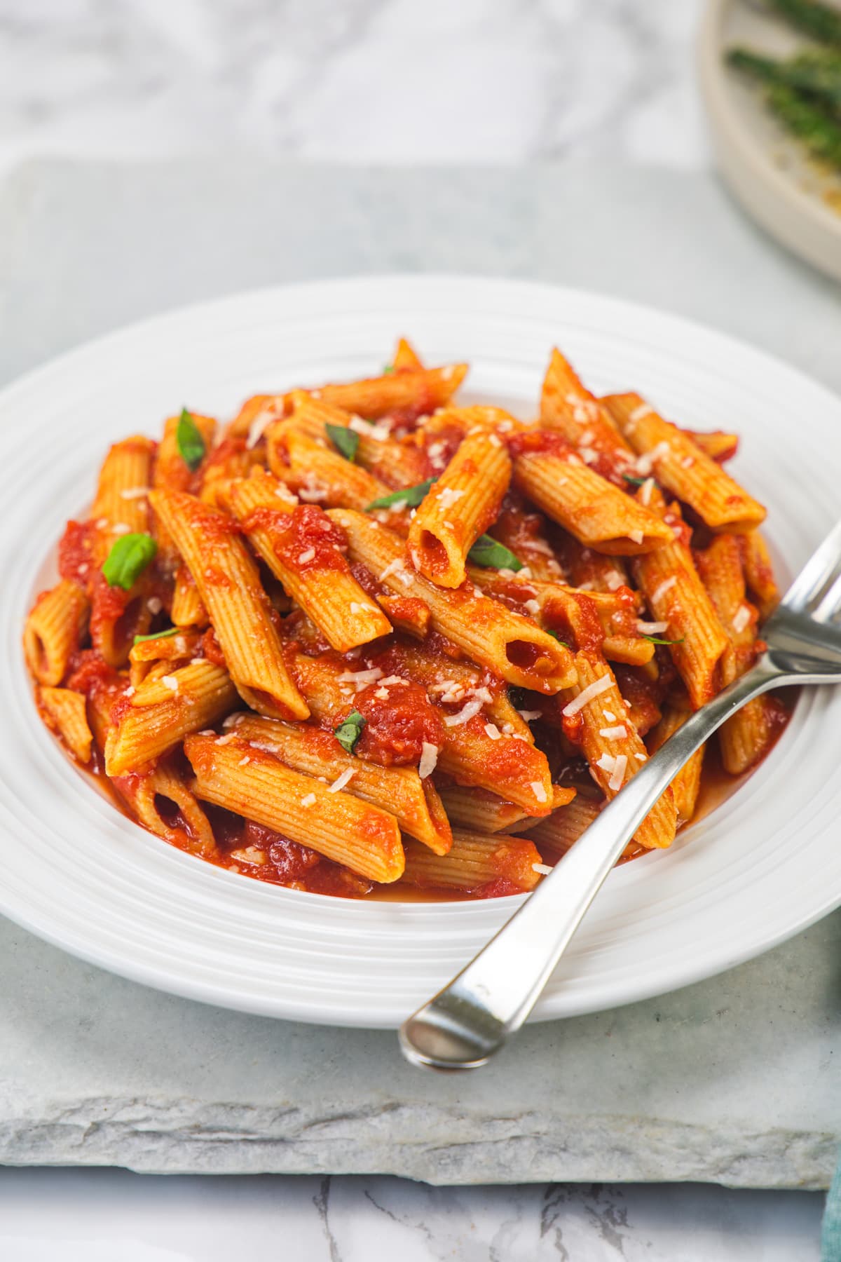 Penne pomodoro served in a plate with fork on the side.