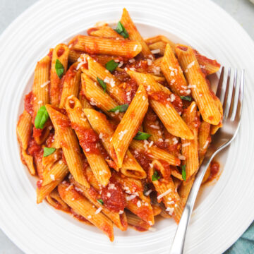 Penne pomodoro garnished with parmesan and basil.