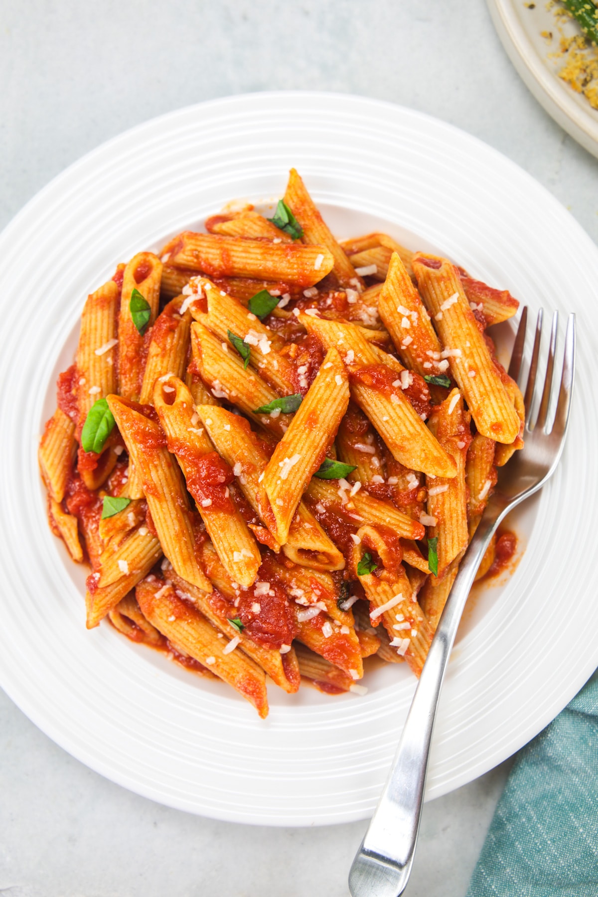 Penne pomodoro garnished with parmesan and basil.