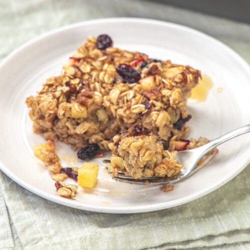 Taking a bite of apple baked oatmeal with a fork.