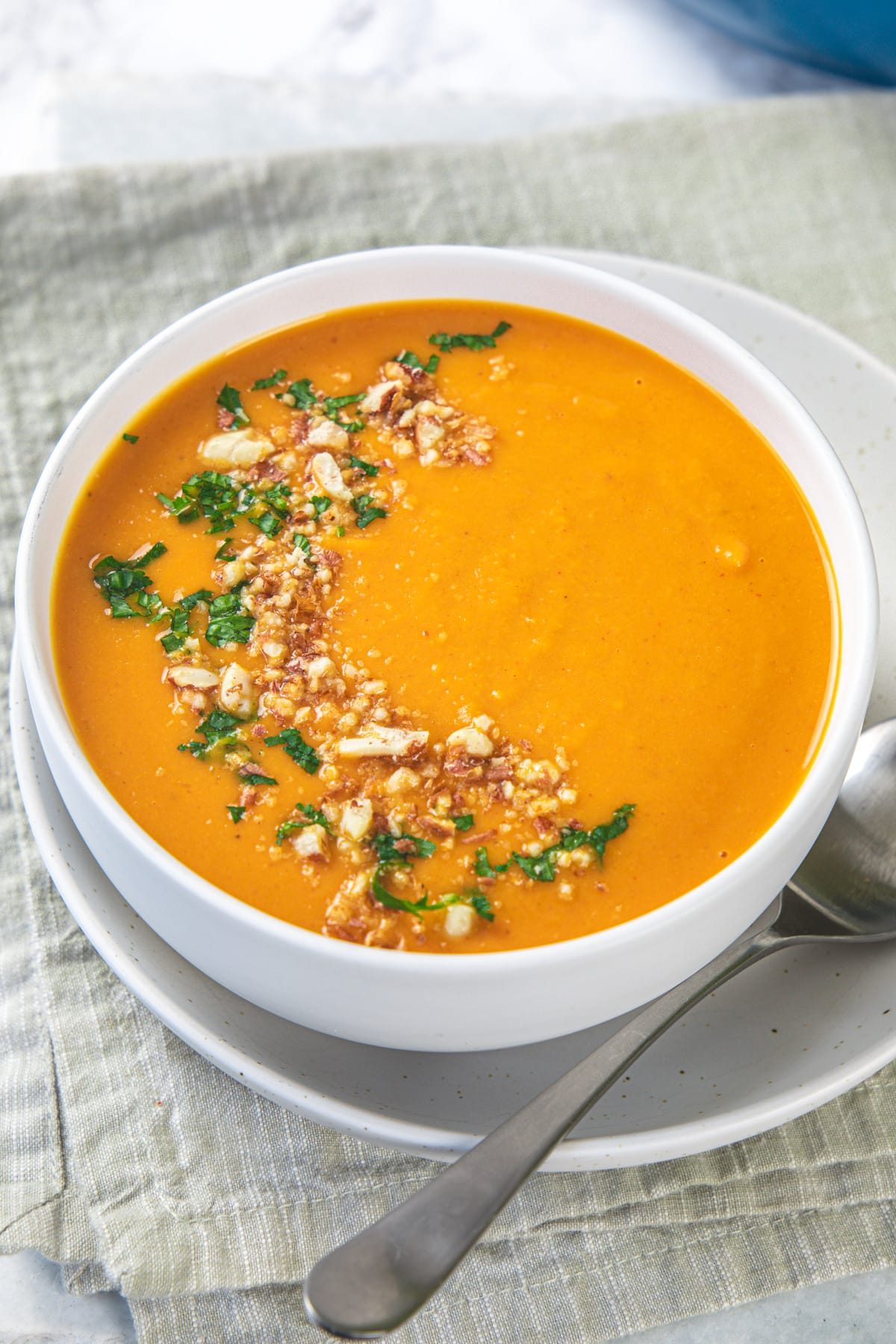 A bowl of curried pumpkin soup garnished with cilantro and crushed peanuts.
