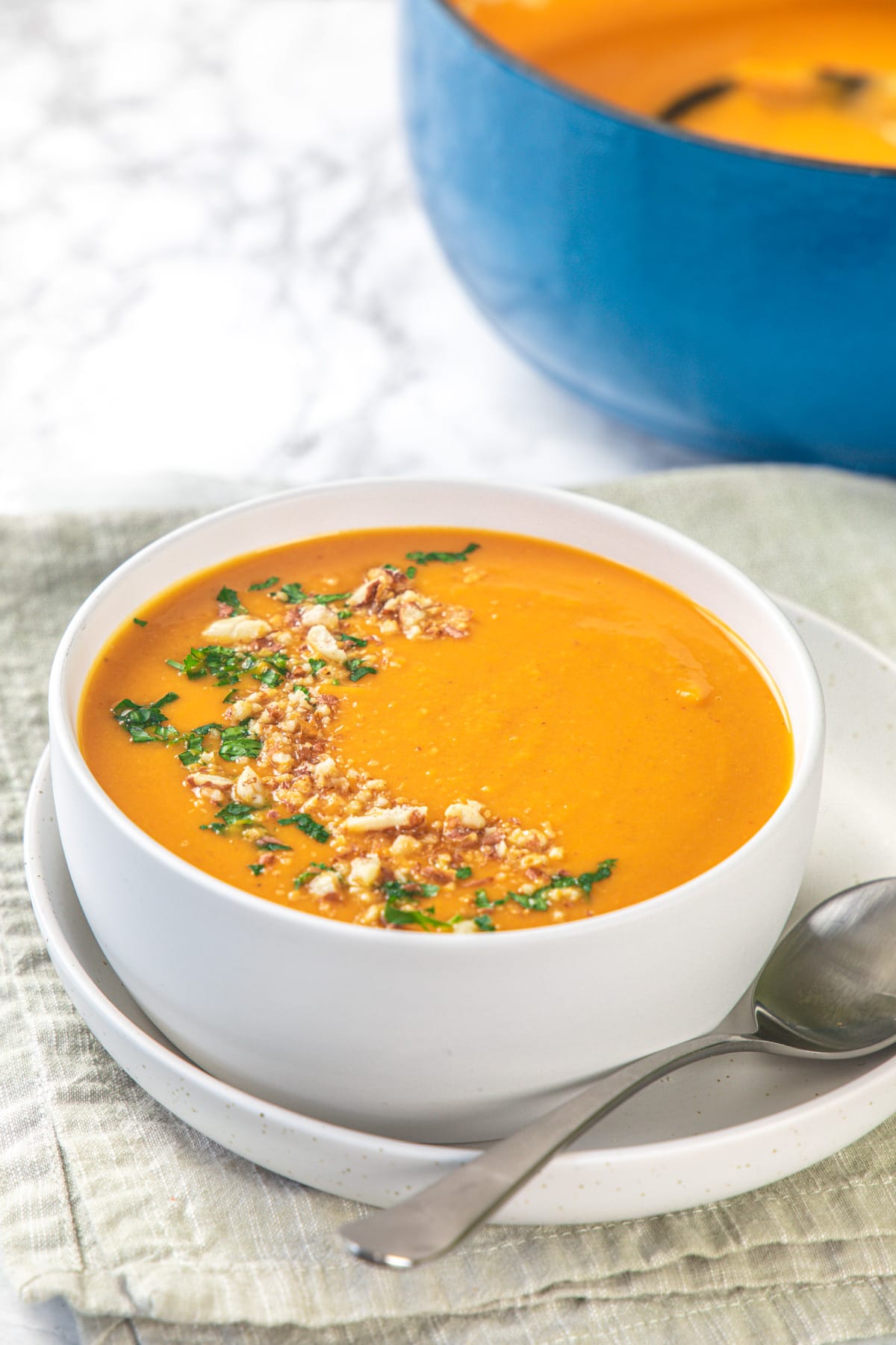 Curried pumpkin soup served in a bowl with spoon on the side.