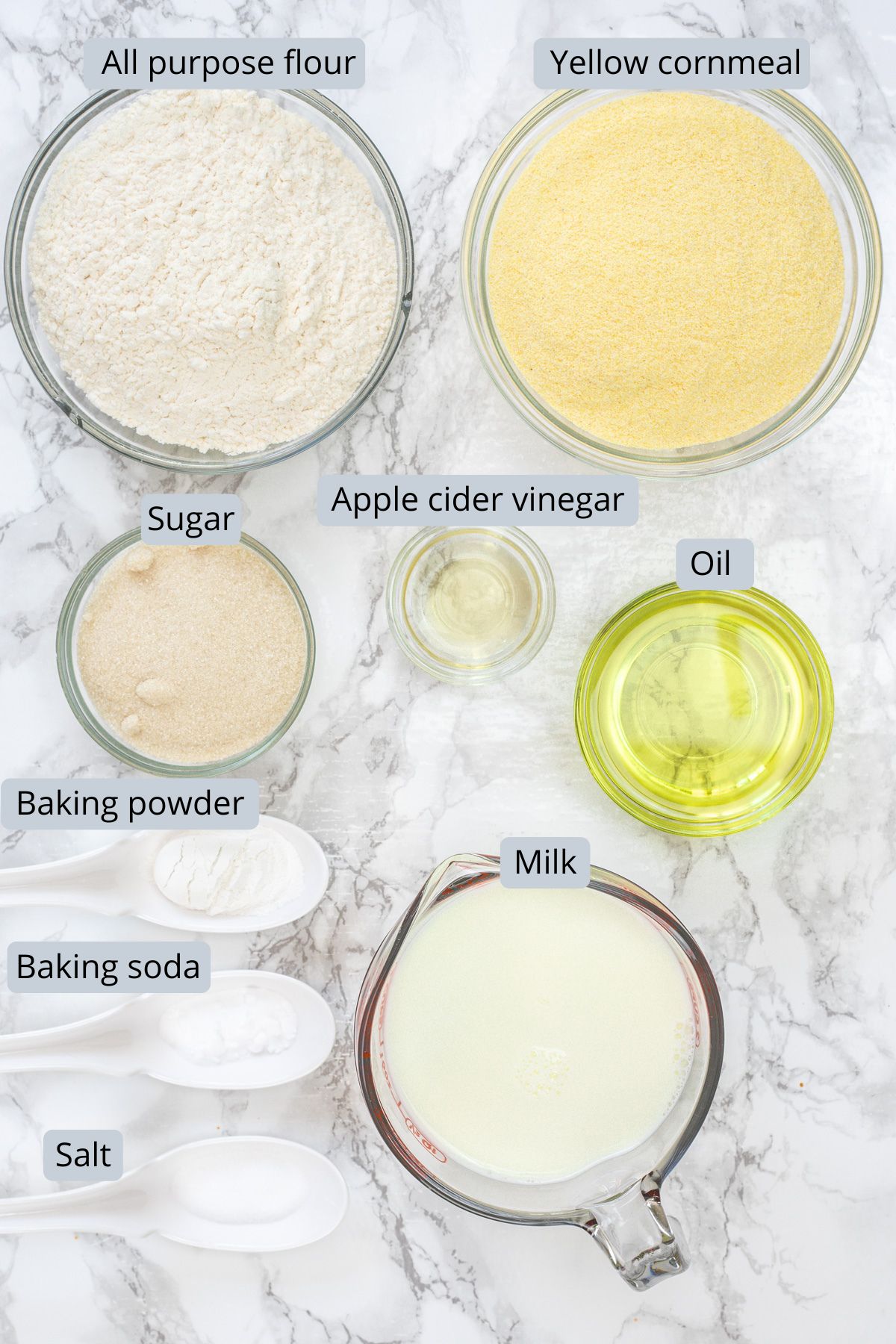 Ingredients in bowls with labels to make cornbread without eggs.