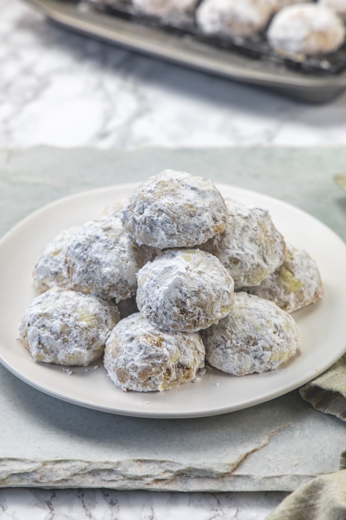 A stack of pecan snowball cookies in a plate.