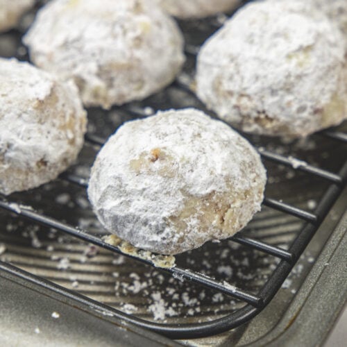 Pecan snowball cookies on a wire rack.