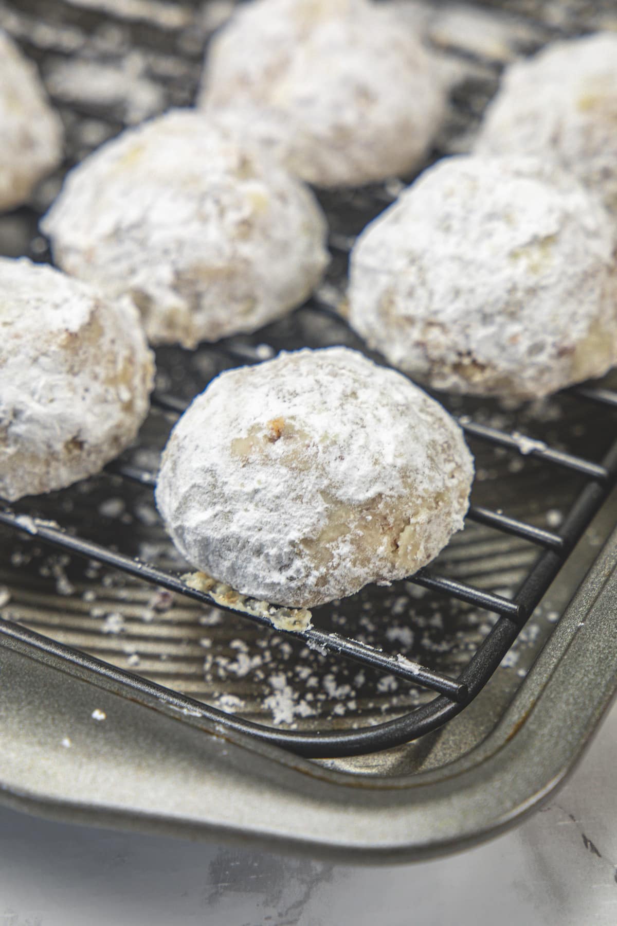 Pecan snowball cookies on a wire rack.