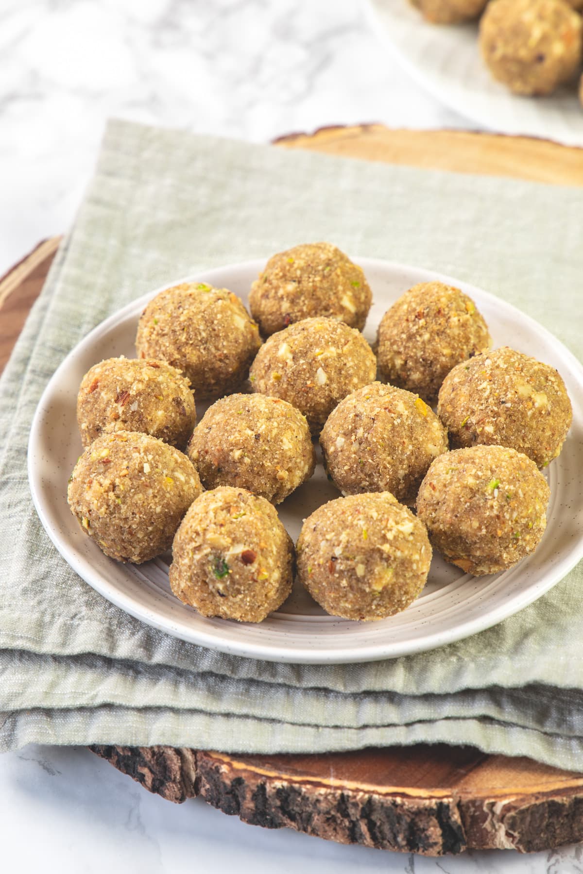 Gond ke laddu in a plate with napkin and wooden board under the plate.