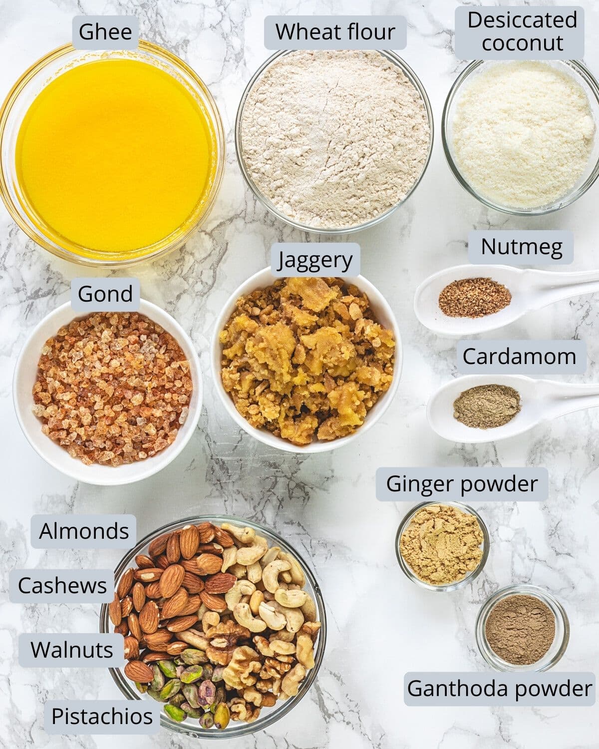 Gond ke laddu ingredients in bowls and spoons with labels.