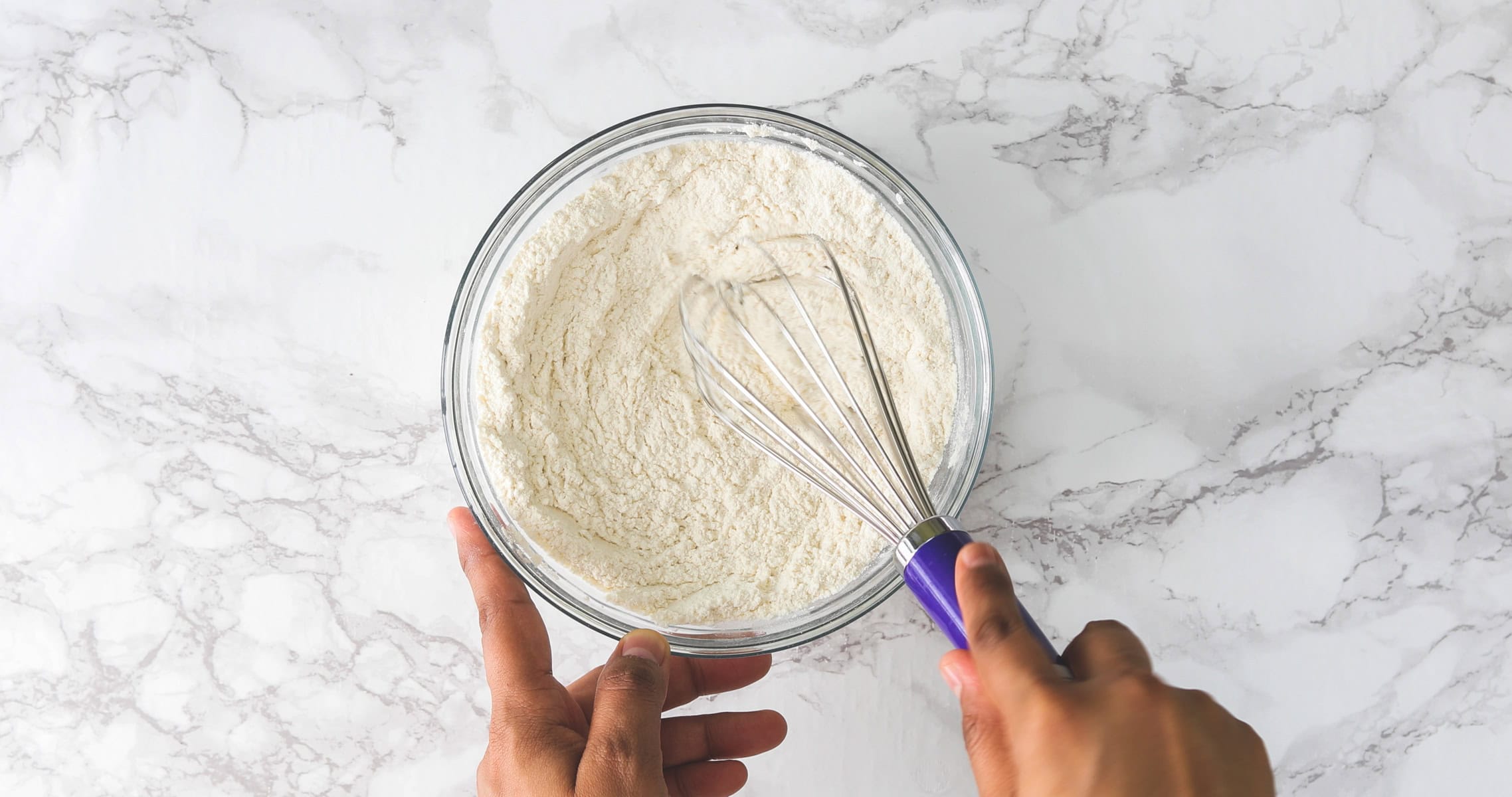 Whisking dry ingredients in a bowl for eggfree peanut butter cookies.