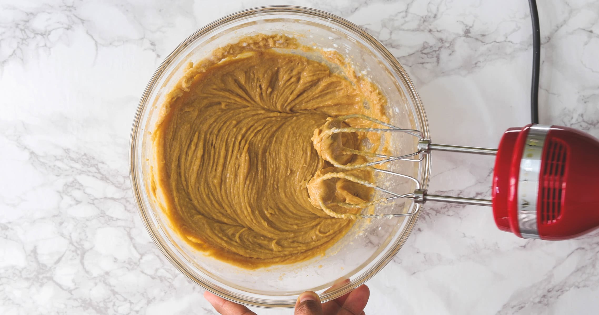 Mixing milk and peanut butter using hand mixer.