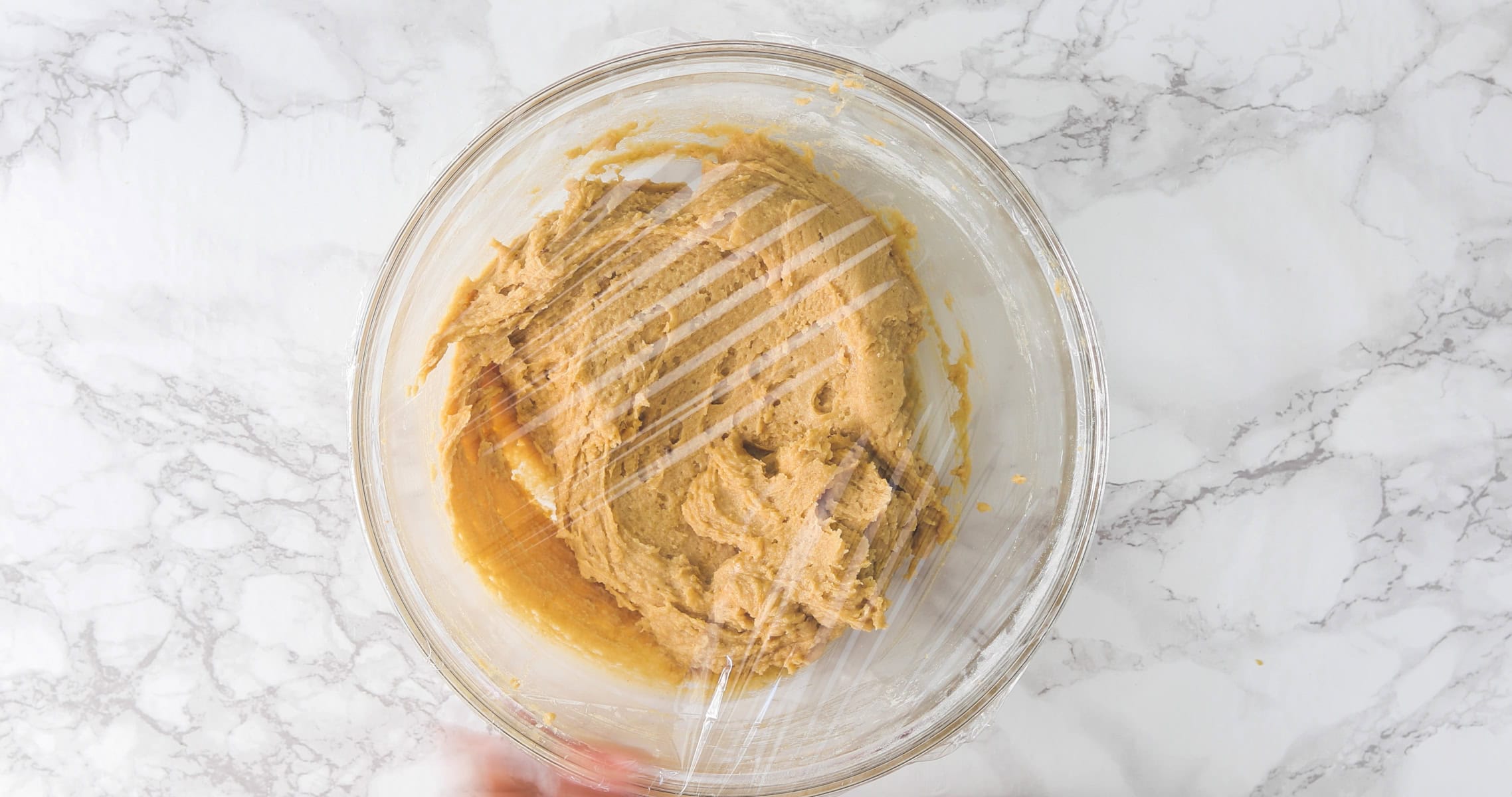 Peanut butter cookie dough bowl cover with plastic wrap.