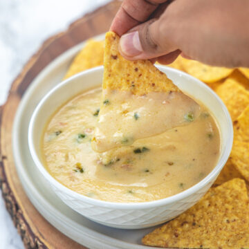 A tortilla chip dipped into queso blanco.