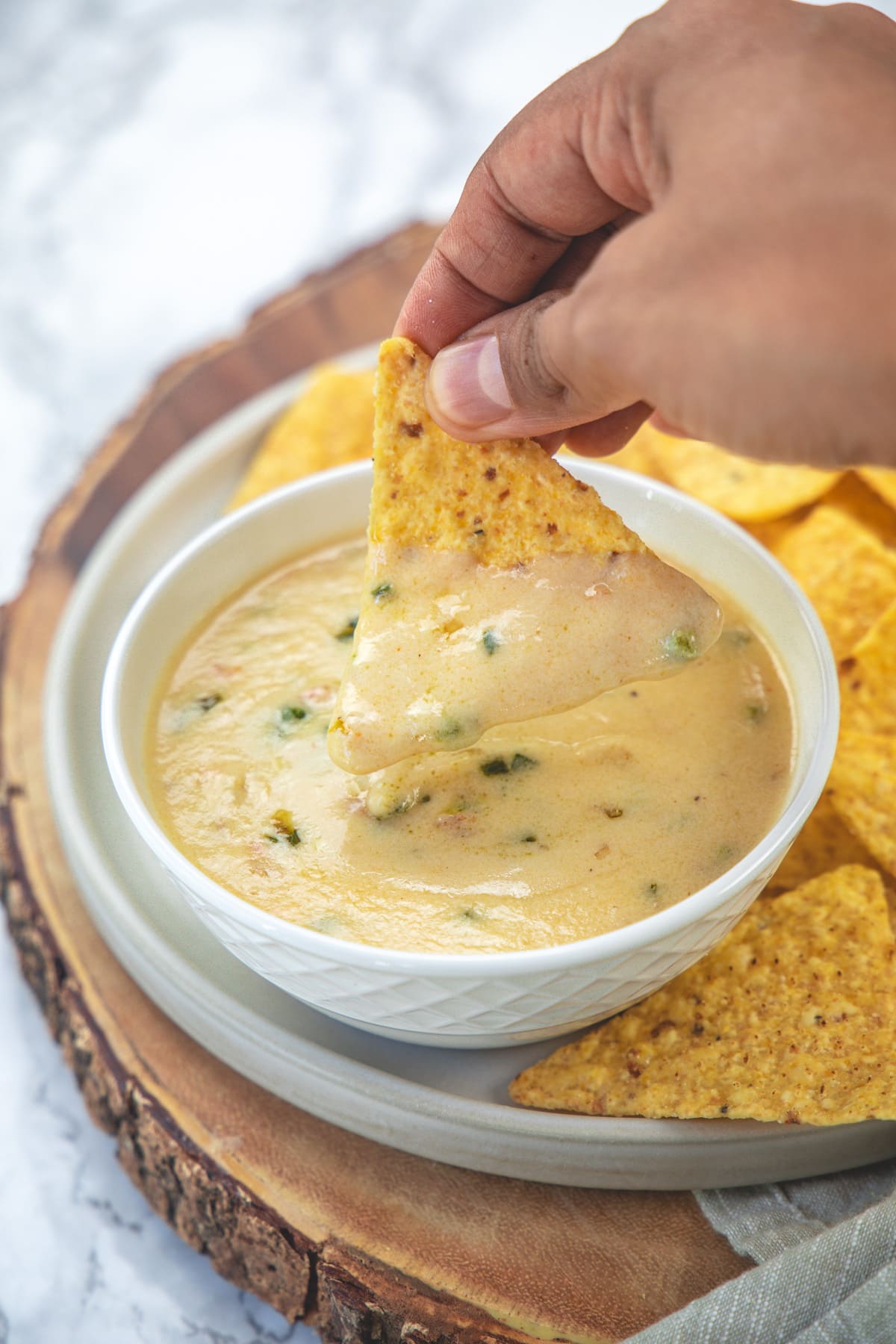 A tortilla chip dipped into queso blanco.