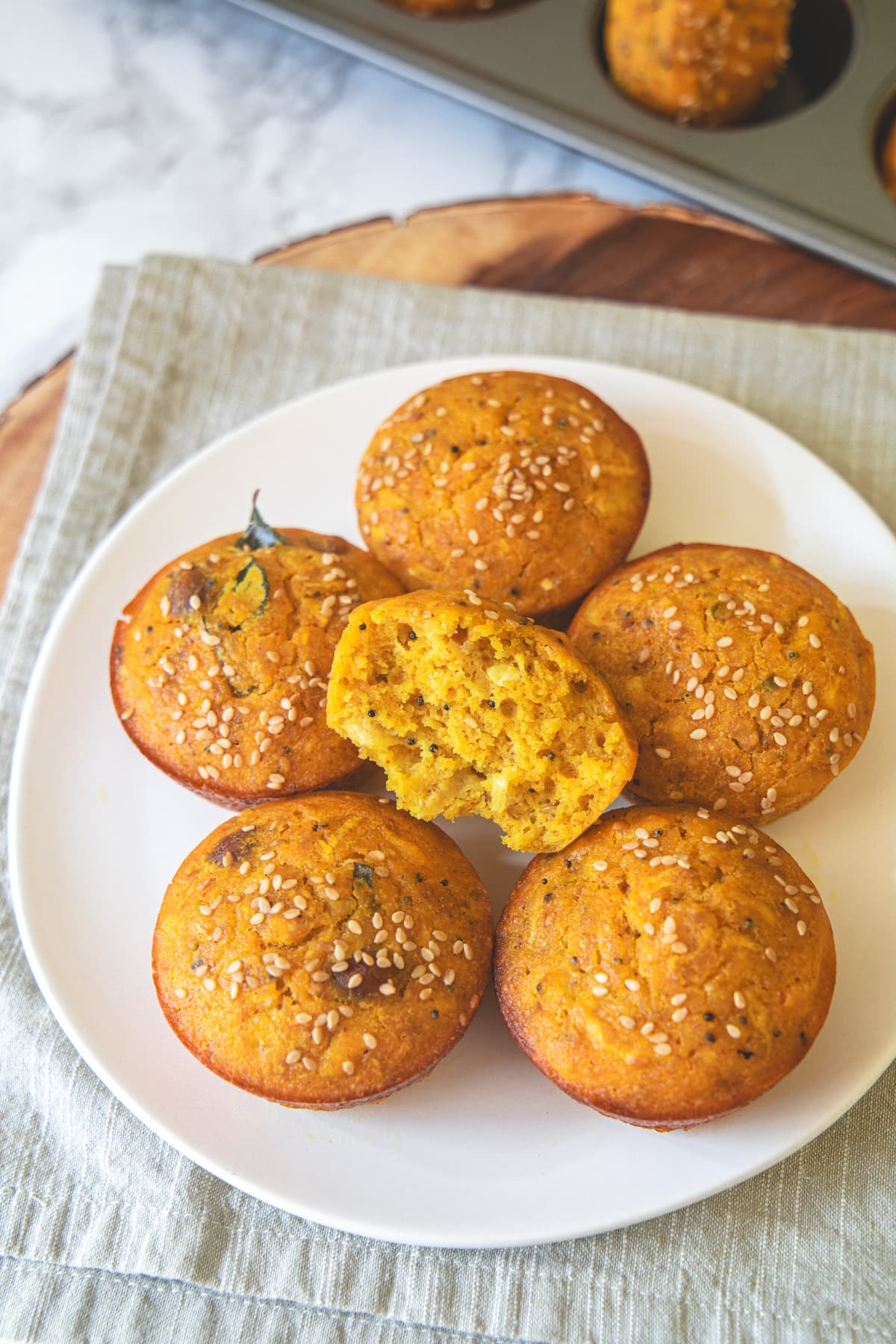 Handvo in muffin shapes in a plate and one is cut into half.