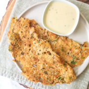 2 jowar dosa with coconut chutney in a plate with napkin and wooden board under it.