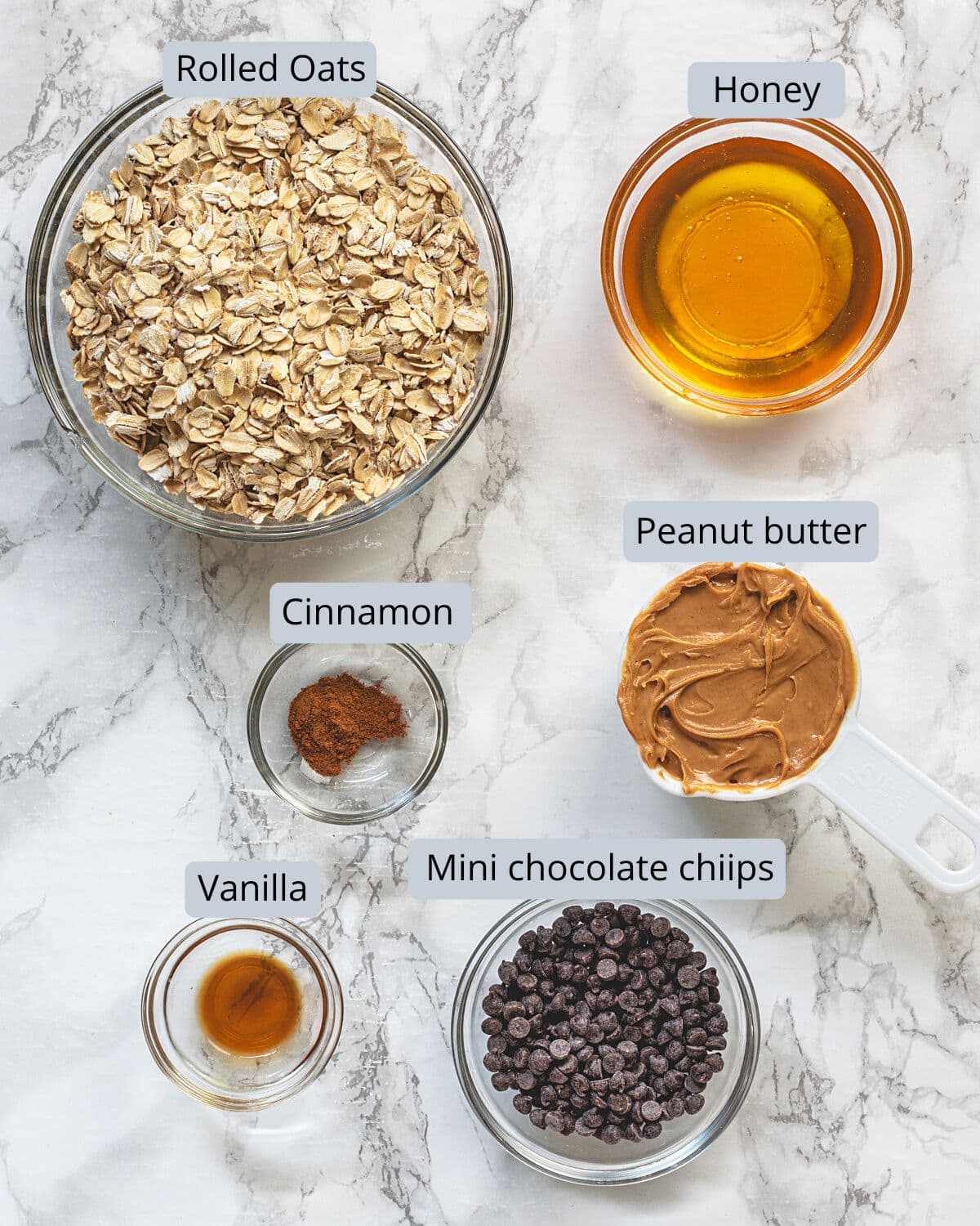 Peanut butter oatmeal balls ingredients in bowls with labels.