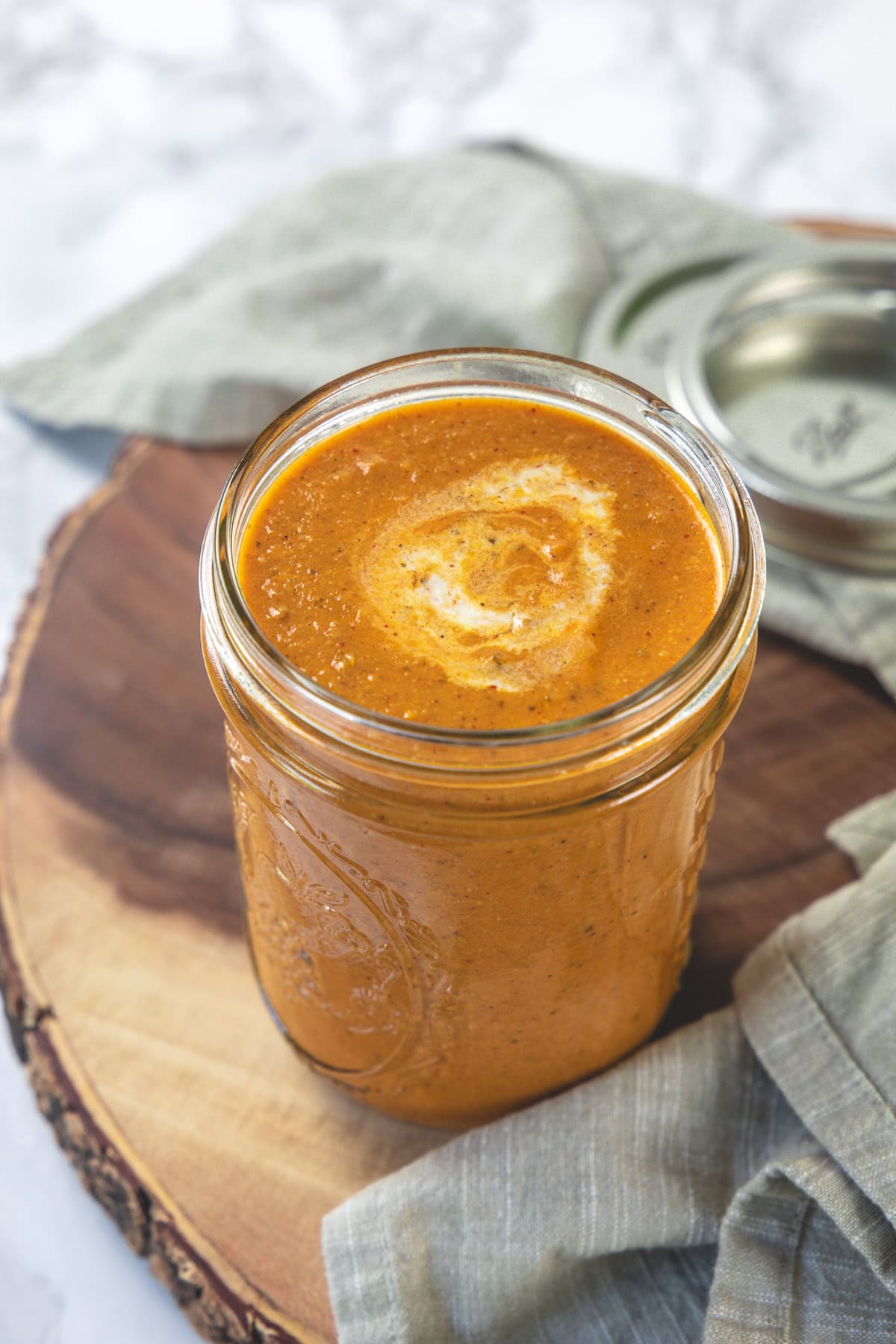 Tikka masala sauce in a mason jar garnished with cream.