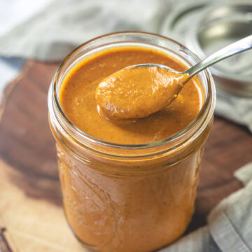 Taking a spoonful of tiika masala sauce from a mason jar.