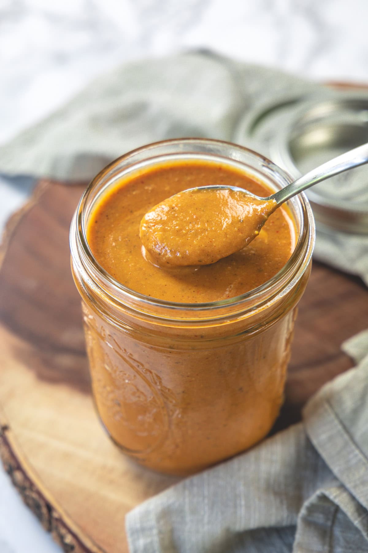 Taking a spoonful of tiika masala sauce from a mason jar.