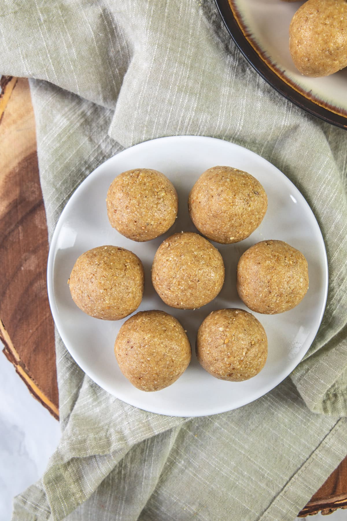 7 peanut ladoo in a plate with napkin on the side.
