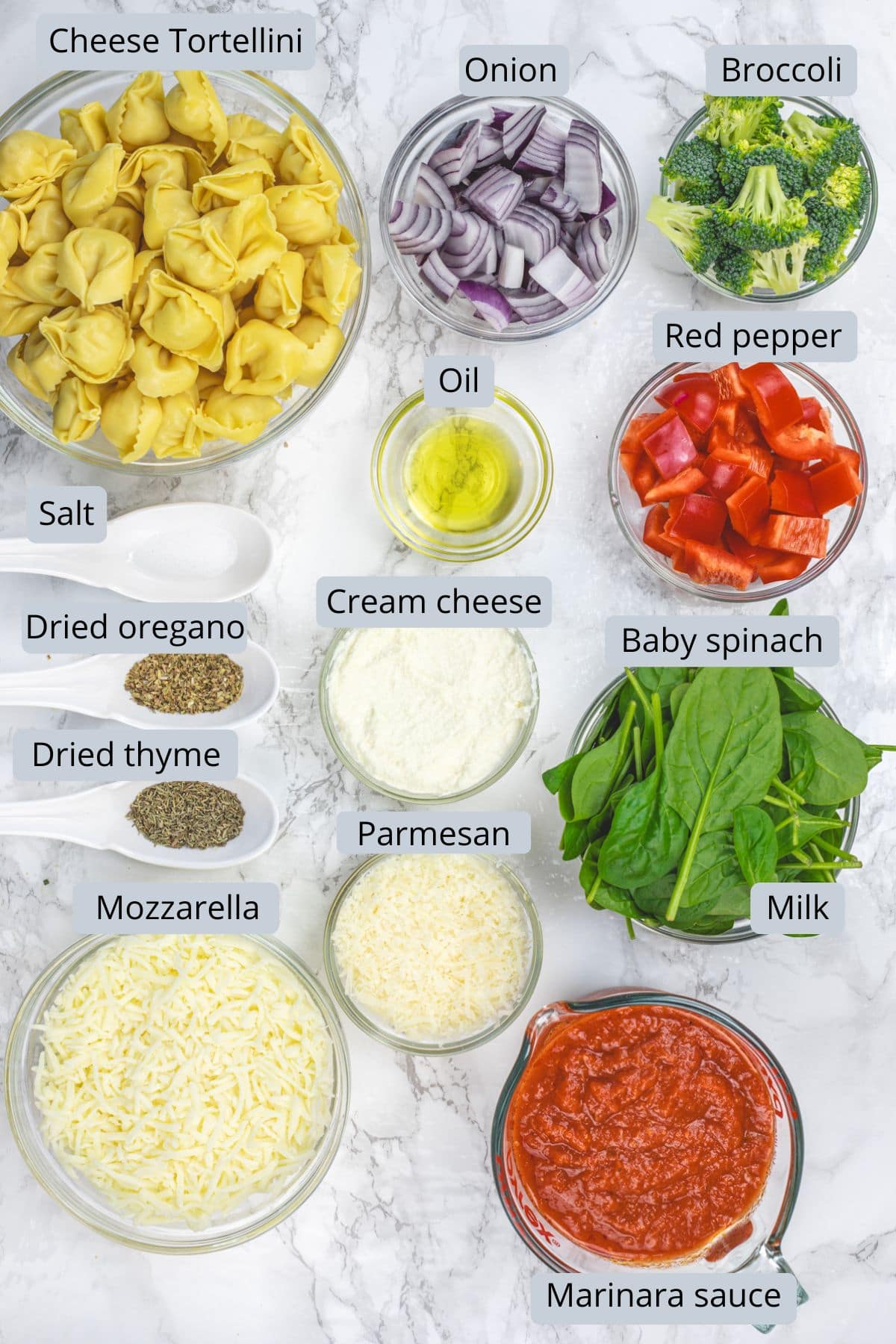 Baked tortellini ingredients in bowls and spoons with labels.