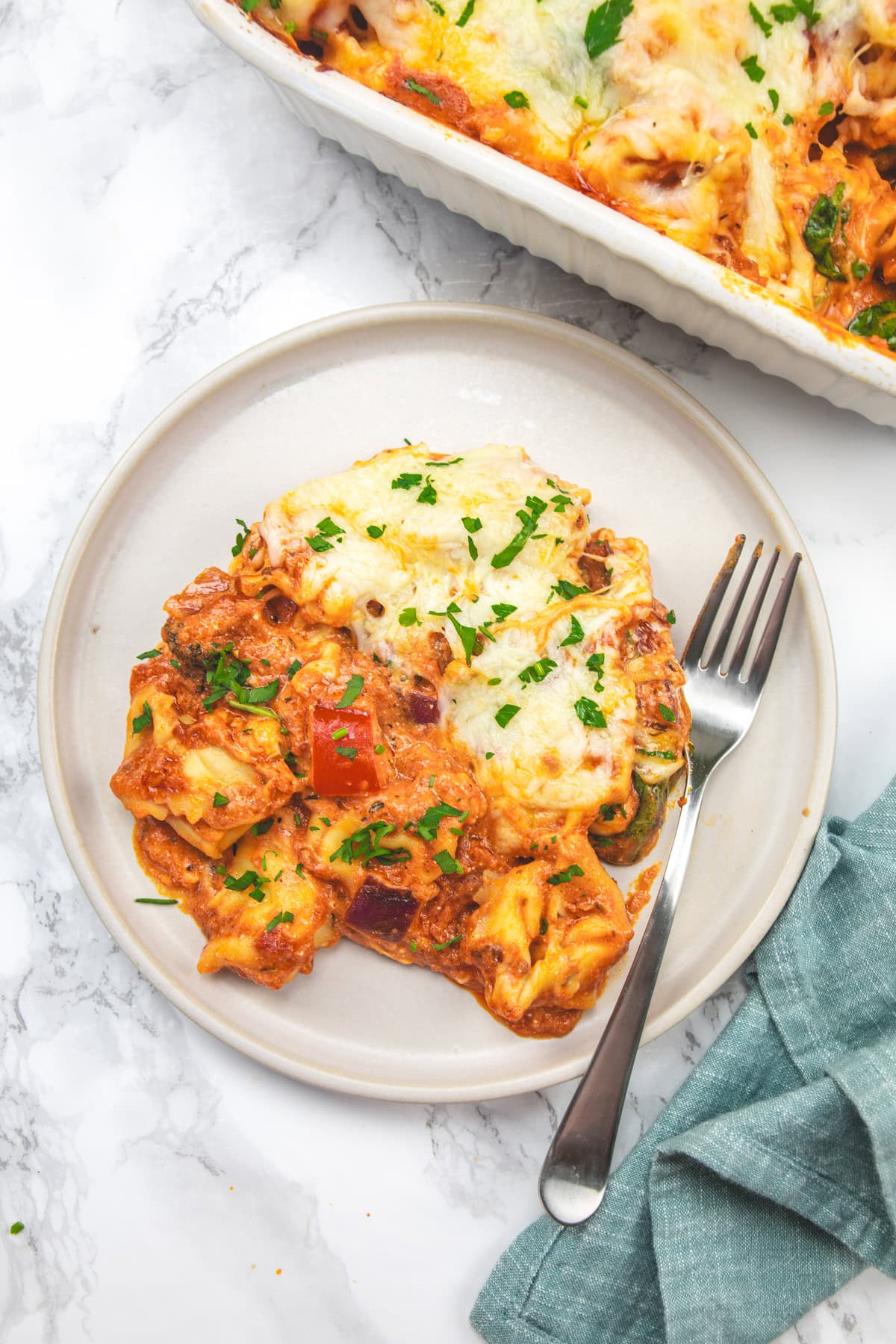 Baked tortellini with vegetables in a plate with fork.