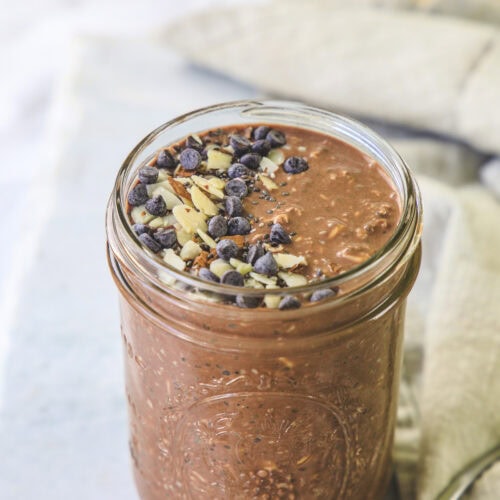 Chocolate overnight oats in a mason jar topped with almonds and chocolate chips.