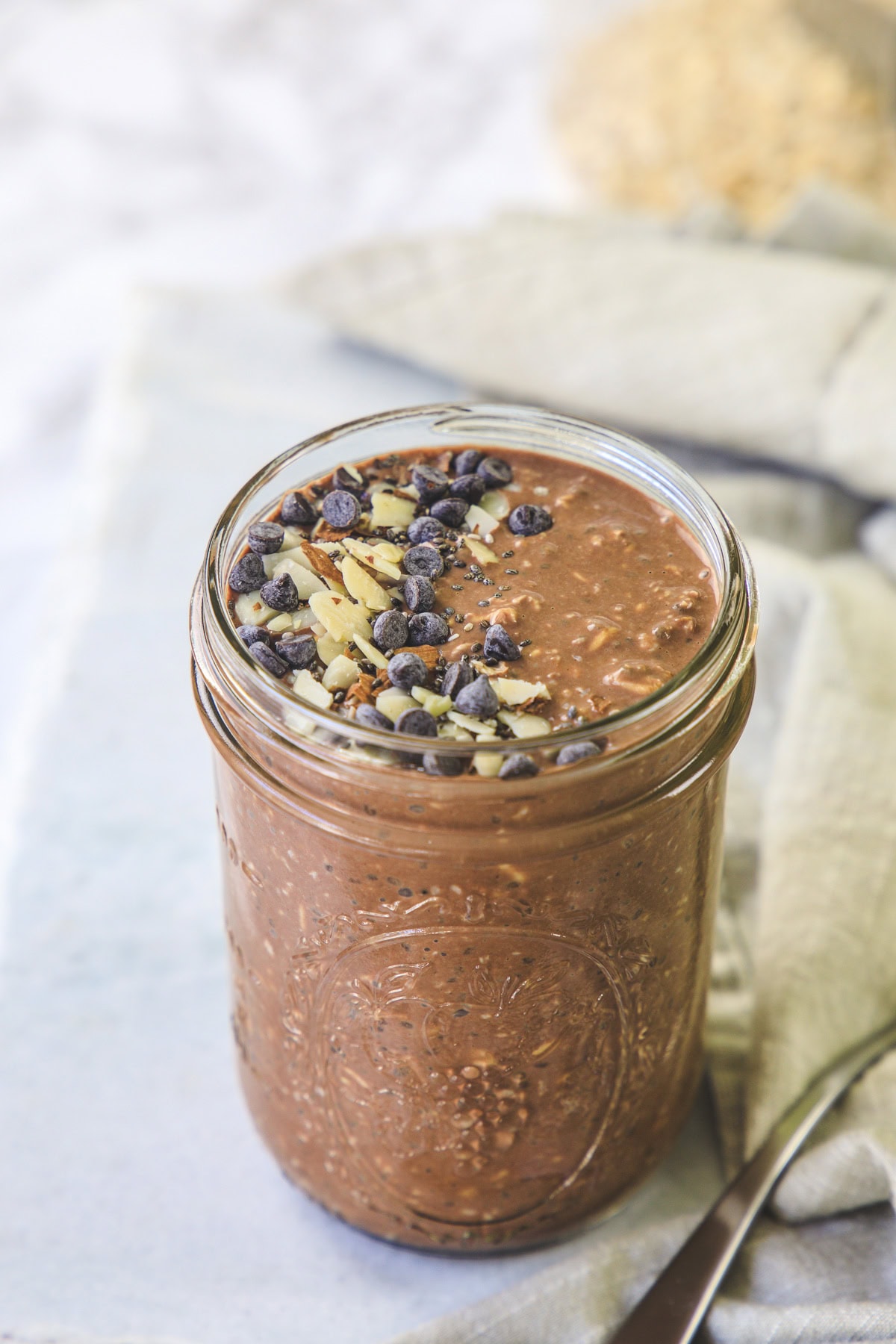 Chocolate overnight oats in a mason jar topped with almonds and chocolate chips.