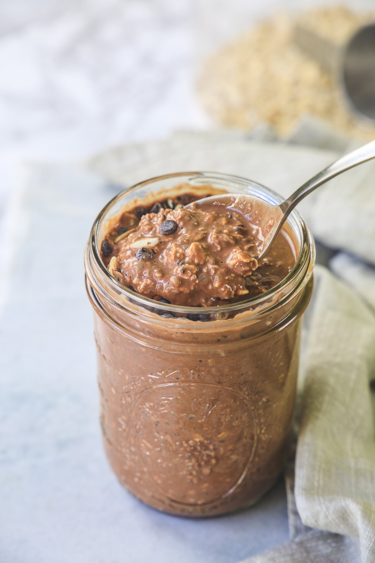 Taking a spoonful of chocolate overnight oats with spoon from the jar.