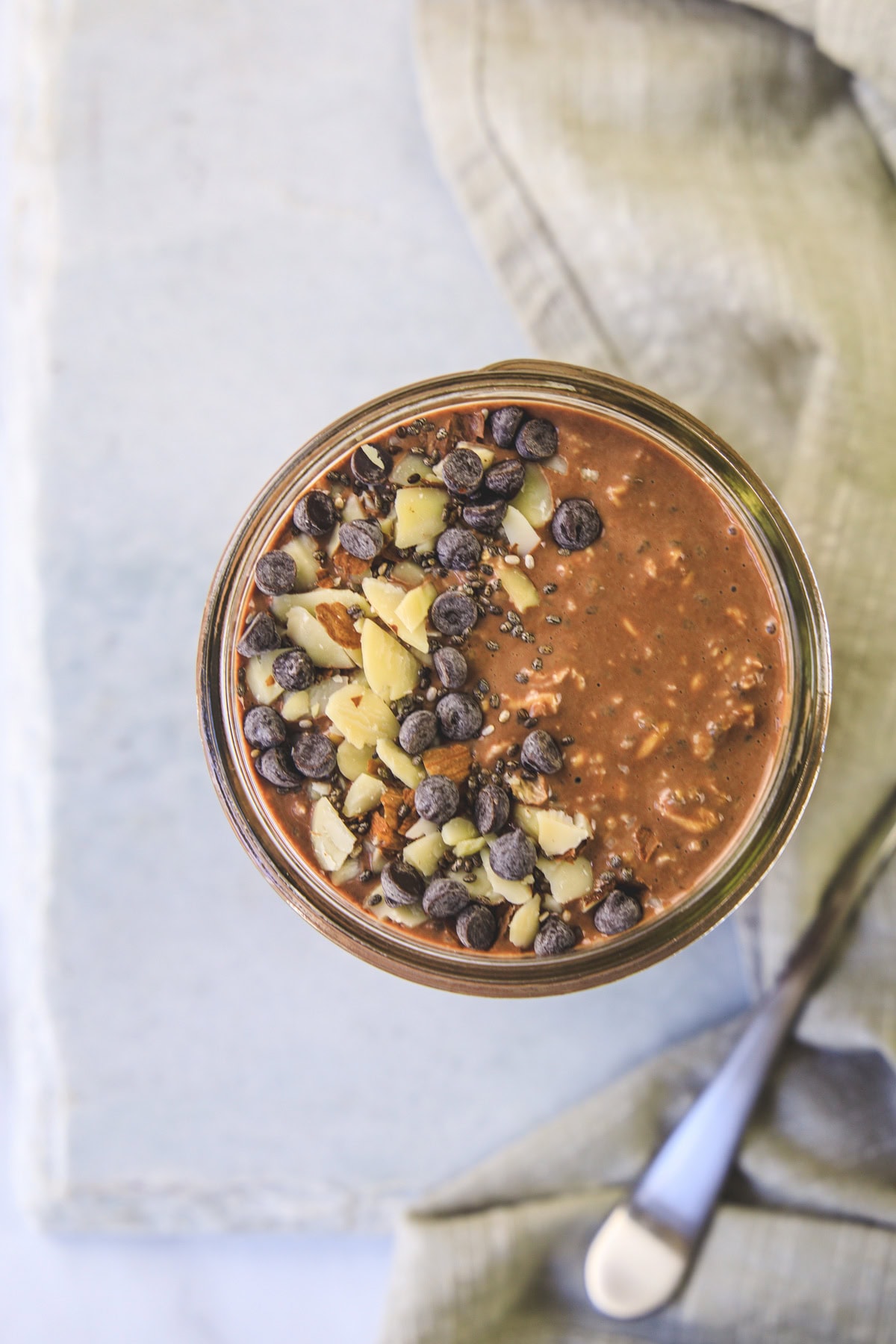 Top view of chocolate overnight oats jar topped with almonds and chocolate chips.