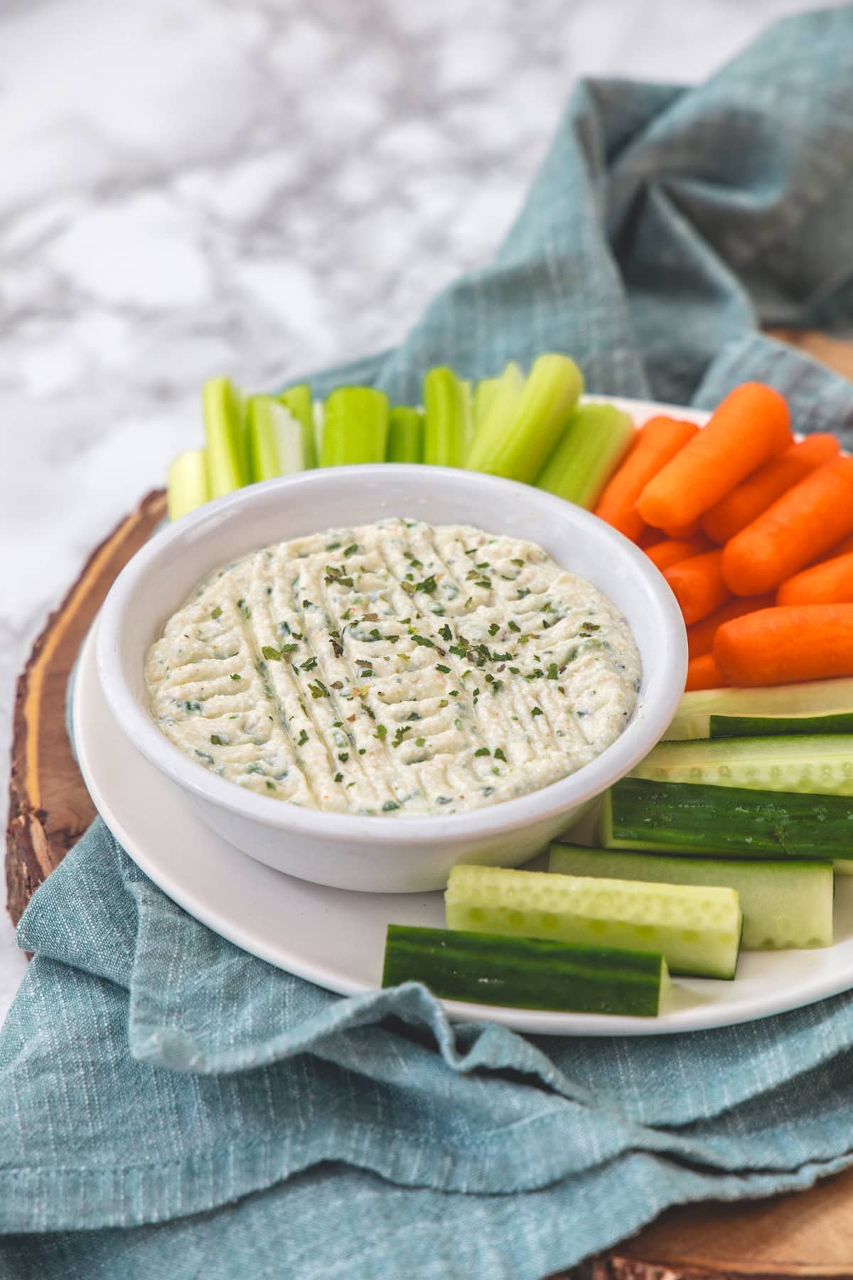 Cottage cheese dip served with veggies in a plate with napkin under it.