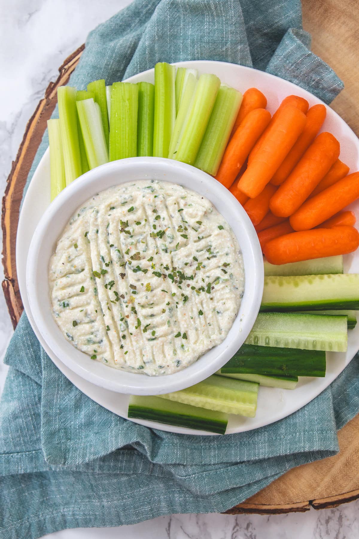 Cottage cheese dip in a bowl with carrots, cucumber and celery in a plate.