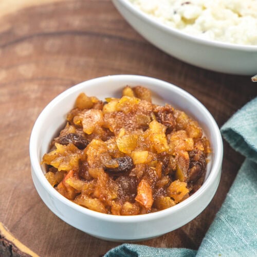 A small bowl of apple chutney with curd rice in the back.