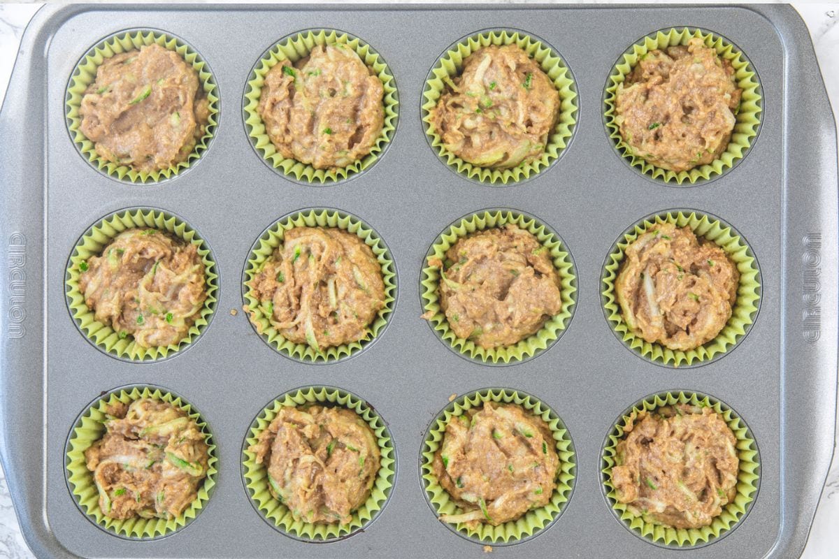 Zucchini muffin batter divided into the muffin pan.