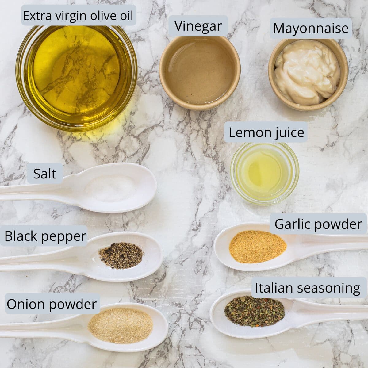 Copycat olive garden salad dressing ingredients in bowls and spoons with labels.