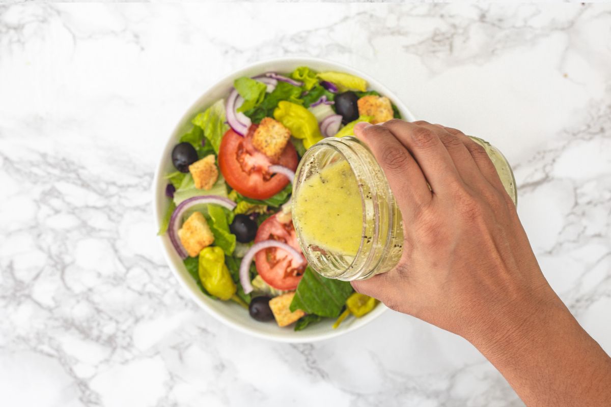 Pouring dressing on the salad.