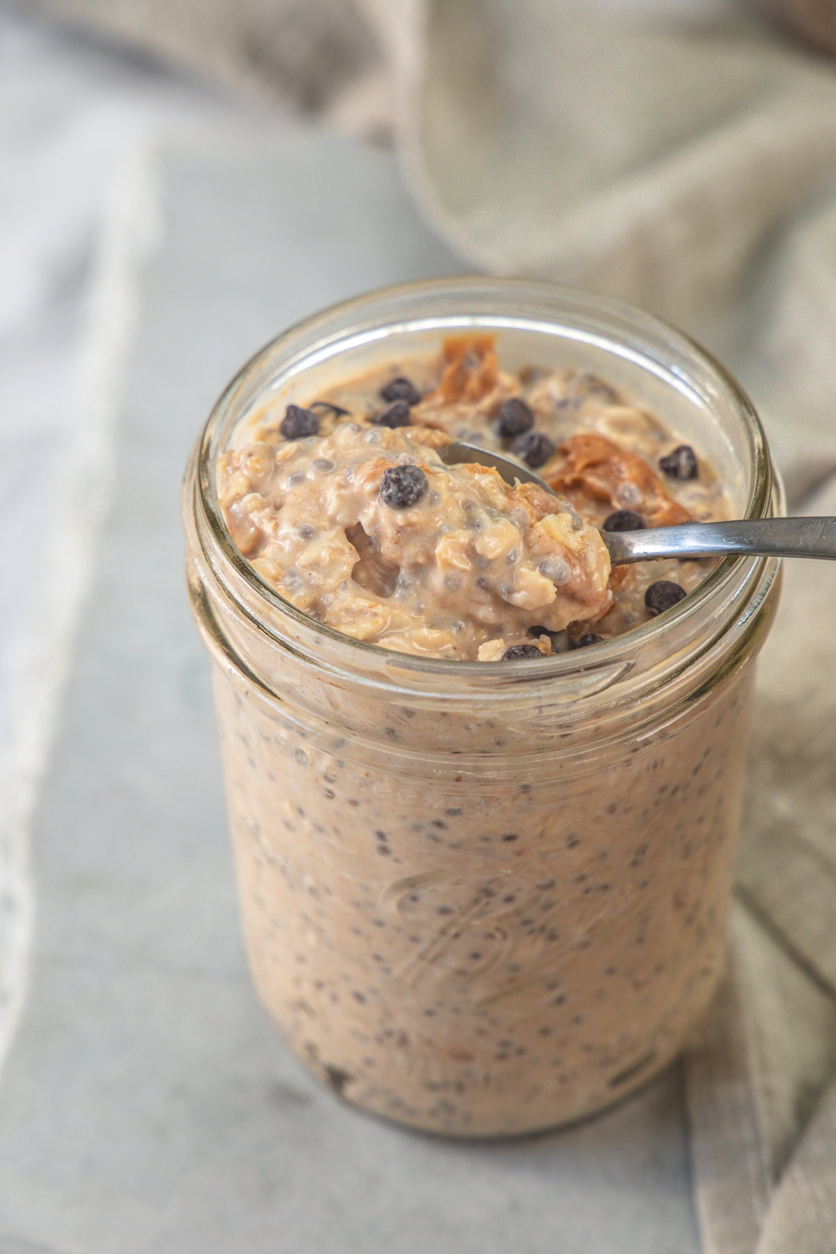 Taking a spoonful of peanut butter overnight oats from a jar.