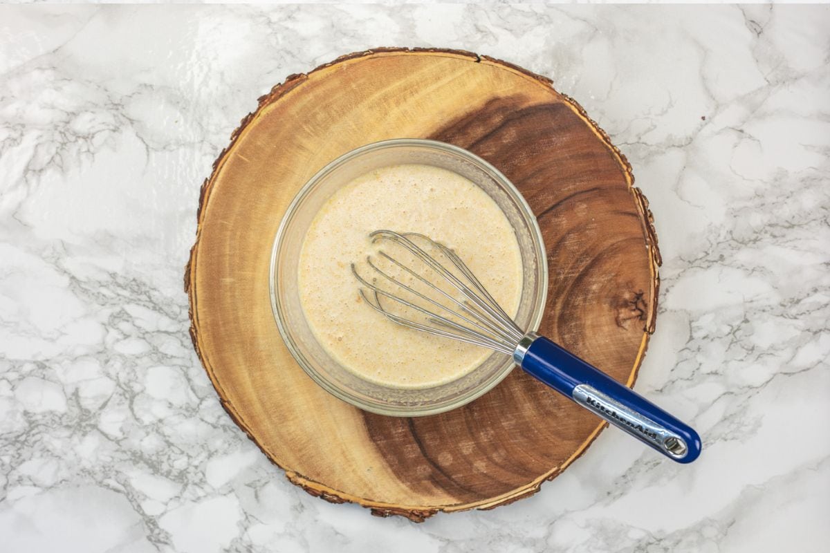 Almond milk, green yogurt, maple syrup and peanut butter whisked together in a bowl.
