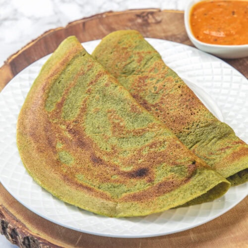 2 Pesarattu on a plate with chutney on the side.