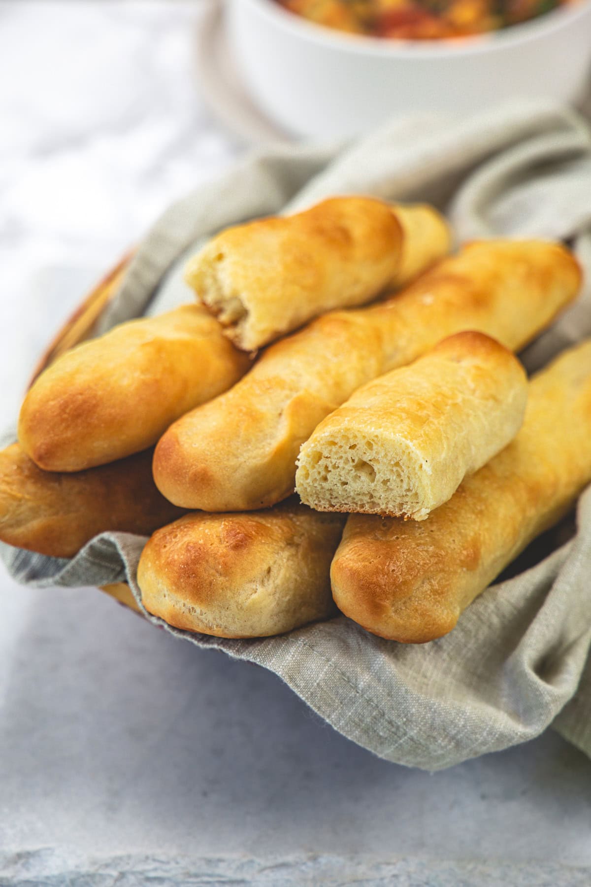 Olive Garden breadsticks in a basket with one bread cut in the half to show texture.